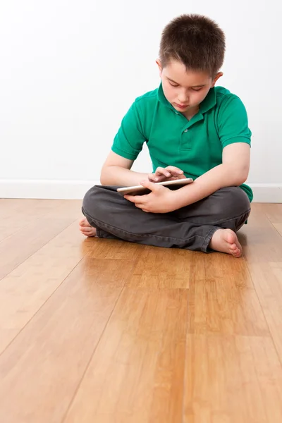 Niño macho lindo sentado en el piso con la tableta — Foto de Stock