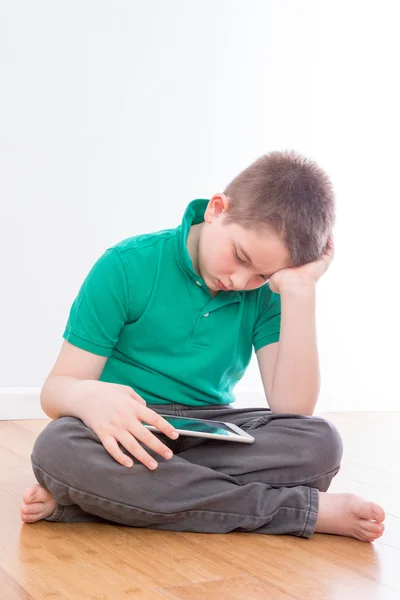 Seriöses männliches Kind liest an seinem Tablet-Computer — Stockfoto