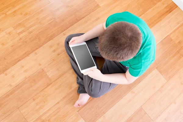 Chłopiec na podłodze trzymając tabletkę w wysokiej kąt widzenia — Zdjęcie stockowe