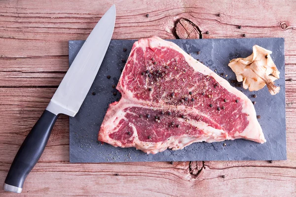 Rått kött på bordet med peppar, Shiitake och kniv — Stockfoto