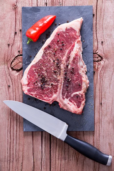 Filete T-Bone en un tablero con sal y pimienta negra —  Fotos de Stock