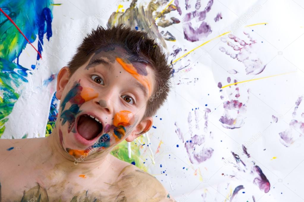 Excited happy little boy doing finger painting