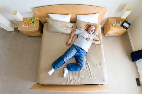 Velký muž ležel rozvalený na postel velikosti king — Stock fotografie