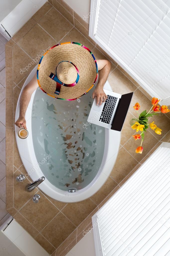 Man relaxing in a bath in a Mexican sombrero