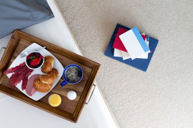Books on Floor Beside Bed with Breakfast Tray