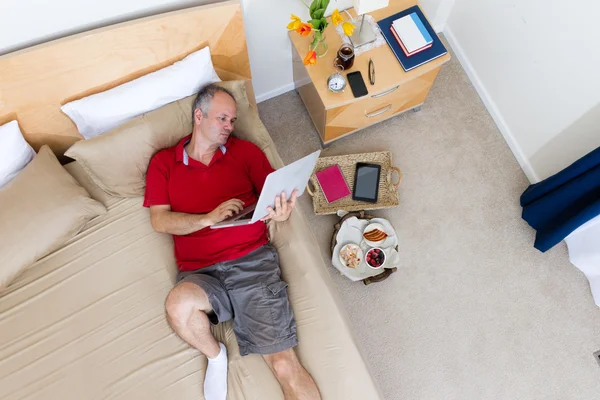 Man Lying on Bed with Laptop in Hotel Room — Stock Photo, Image