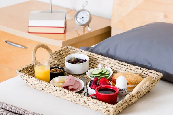 Frühstückstablett auf ungemachtem Bett im Hotelzimmer — Stockfoto