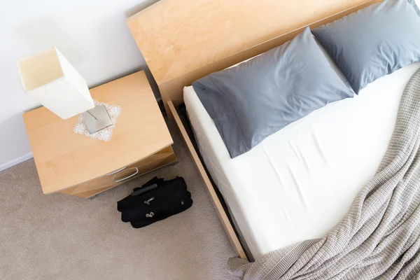 Svart väska på golvet bredvid obäddade säng i hotellrum — Stockfoto
