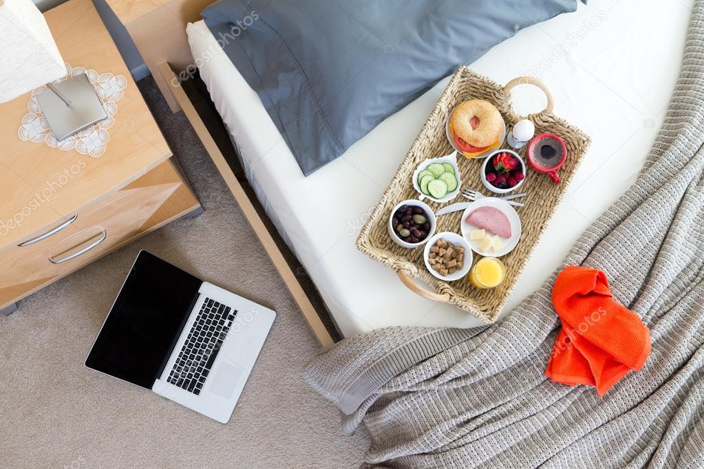 Laptop on Floor Beside Bed with Breakfast Tray