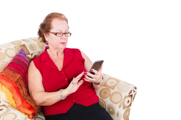 Ανώτερος γυναίκα κάθεται στον καναπέ χρησιμοποιώντας το τηλέφωνό της — Φωτογραφία Αρχείου