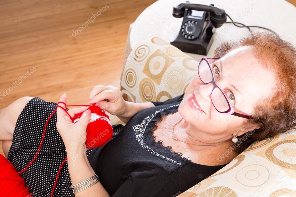 Elderly grandmother sitting knitting in a chair