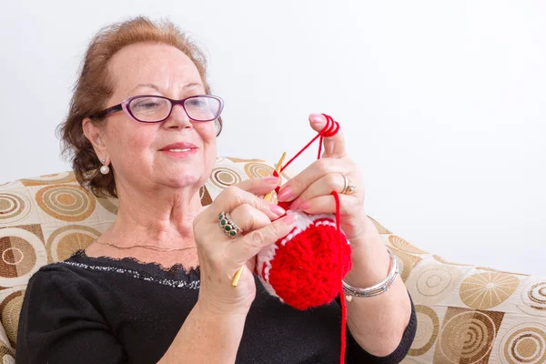 Senior lady sitting knitting at home — Stock Photo, Image