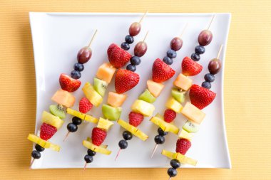 Fresh fruit shish kebabs on a modern square plate
