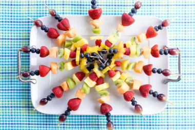 Healthy fresh fruit kebabs on a picnic table