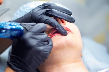 Dövme makinesiyle dudaklara kalıcı makyaj uygulanması süreci. Kalıcı aygıt iğnesi