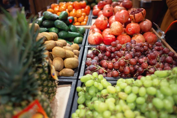 トロピカルフルーツショップでは様々なフルーツやベリーが販売されています。ブドウ、パイナップル、ザクロとのカウンター — ストック写真