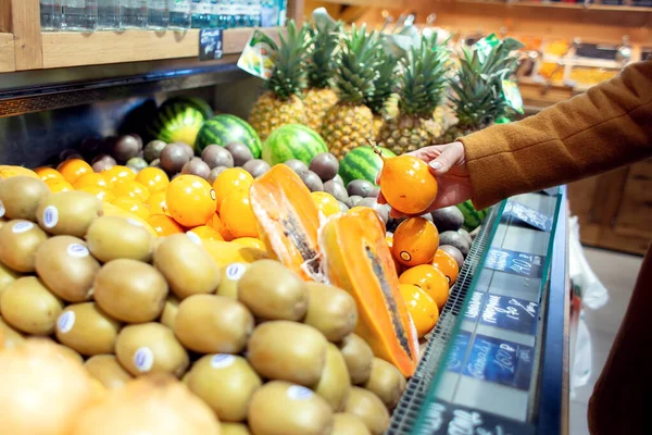 Woman chooses exotic fruits in the store. Granadilla on the counter of the store