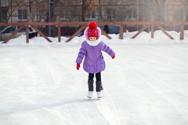 소녀는 겨울에 아이스 위에서 스케이트를 탑니다 도시의 뜰에서 덜커덩거리는 소리가 스톡 사진