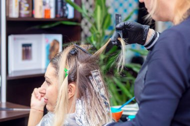 Güzellik salonunda saç boyama işlemi. Kuaför müşterinin saçını boyar. Güzellik sektörü çalışanı. Saç boyama.