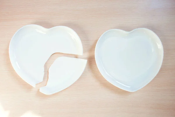 Broken heart-shaped plate. Cracked heart. Shards of broken dishes. Broken heart and whole. Collapse