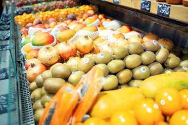 Mağazadaki tezgahın üzerinde çeşitli egzotik meyveler var. Nar, kivi, mango ve diğer egzotik ürünler satılır.