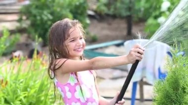 Mayolu bir kız bahçe hortumundan su sıçratıyor. Yazın bir çocuk, bir hortumla bahçede yıkanır.