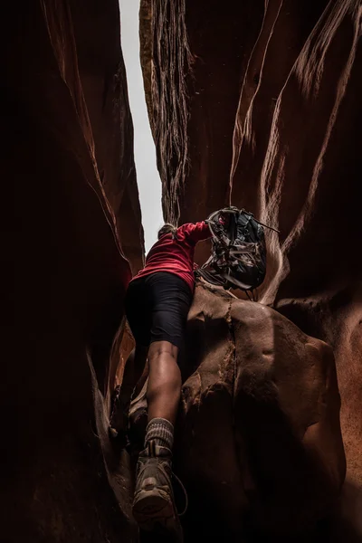 Frau mit Rucksack klettert über großen Felsbrocken — Stockfoto