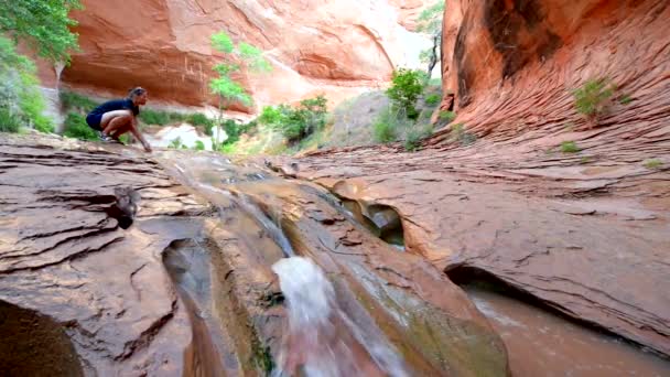 Gelukkig wandelaar opspattend water in mooie Cascade in Coyote Gulch — Stockvideo