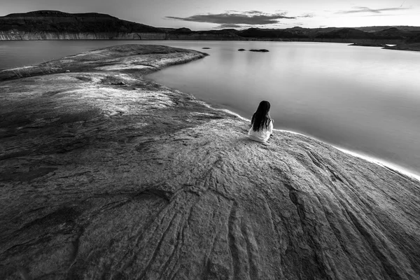 Одинока жінка сидить біля озера чорно-біла — стокове фото