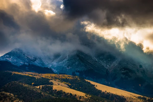 Solen skiner genom mörka moln över bergen sanddyn — Stockfoto