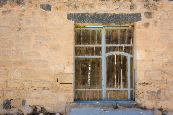 Ancient wooden door set in stone wall — Stock Photo, Image