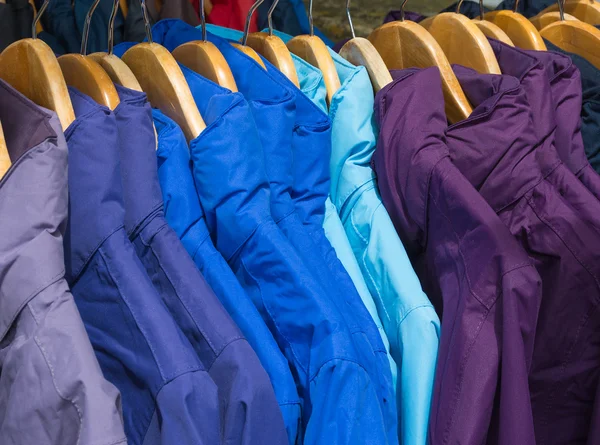 Rainproof jackets in bright colors on a rack for sale. — Stock Photo, Image