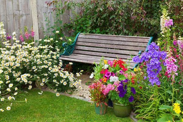 Jardim de casa de campo com banco e recipientes cheios de flores — Fotografia de Stock