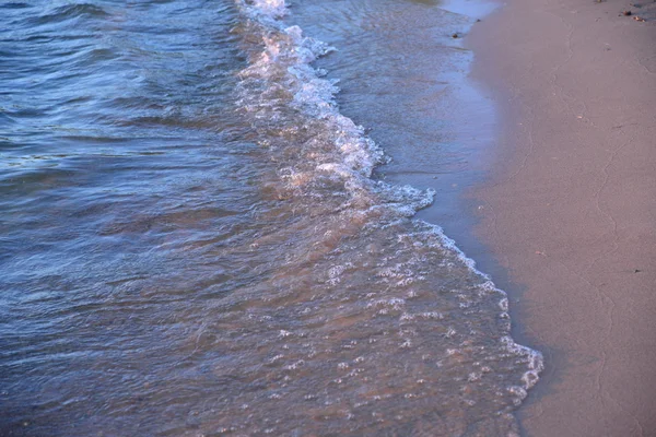 Sea wave foam on a sandy beach at sunset — Stock Photo, Image