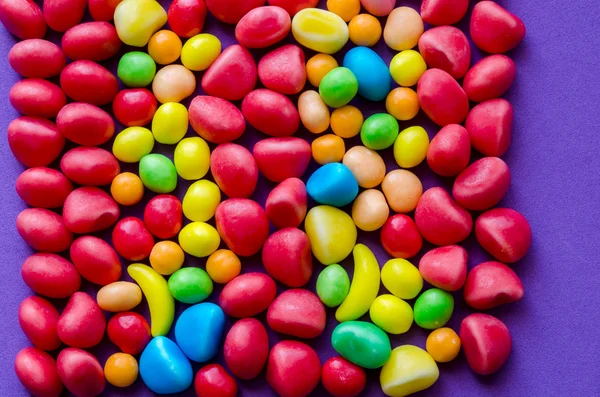 A lila háttér színes cukorkák — Stock Fotó