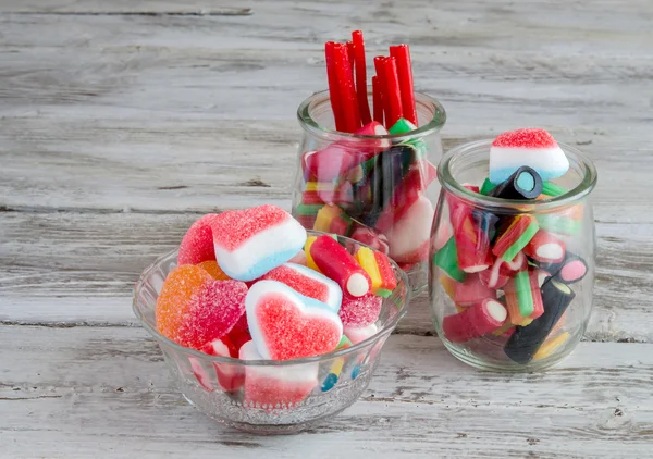Lakritze, Bonbons und Süßigkeiten in Glasgefäßen auf Holztisch — Stockfoto