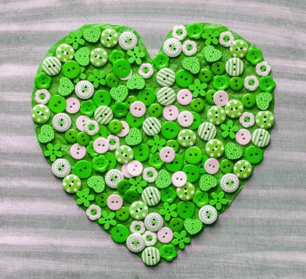 Green heart covered with colorful buttons. — Stock Photo, Image