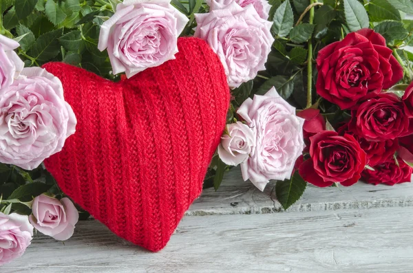 Gecontroleerd handgemaakte hart tegen van rode en roze rozen — Stockfoto