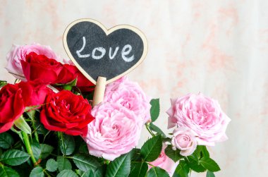 El yapımı ahşap kalp kırmızı ve pembe güller arasında