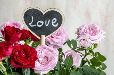 El yapımı ahşap kalp kırmızı ve pembe güller arasında