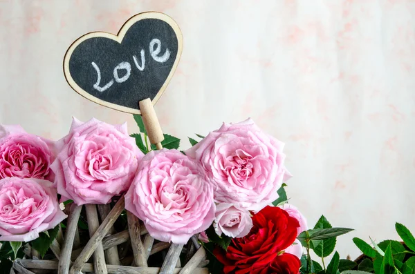 Cuore in legno fatto a mano tra rose rosse e rosa — Foto Stock