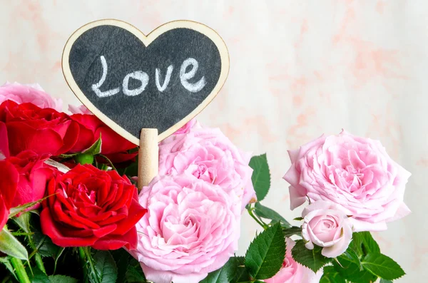 Corazón de madera hecho a mano entre rosas rojas y rosas rosadas — Foto de Stock