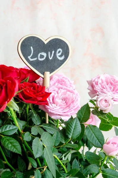 Corazón de madera hecho a mano entre rosas rojas y rosas rosadas —  Fotos de Stock