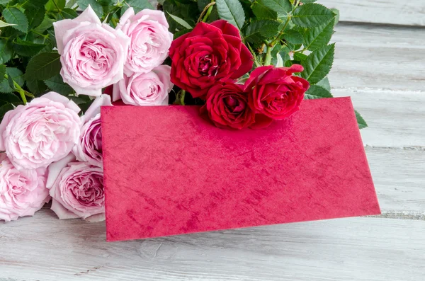 Μπουκέτο με κόκκινα τριαντάφυλλα με κόκκινη ξύλινη σανίδα στο τραπέζι — Φωτογραφία Αρχείου