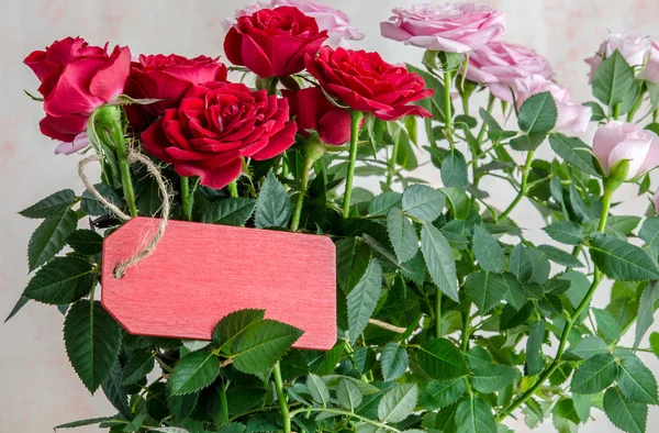 Ramo de rosas rojas con tablón de madera roja en la mesa —  Fotos de Stock