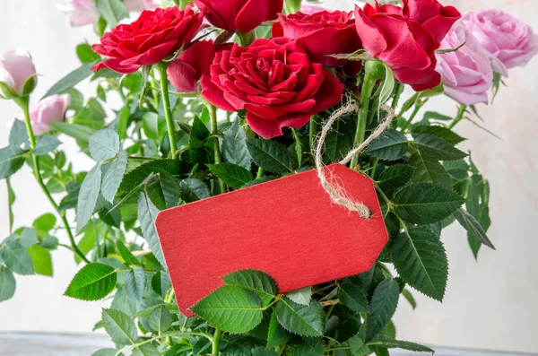 Ramo de rosas rojas con tablón de madera roja en la mesa — Foto de Stock