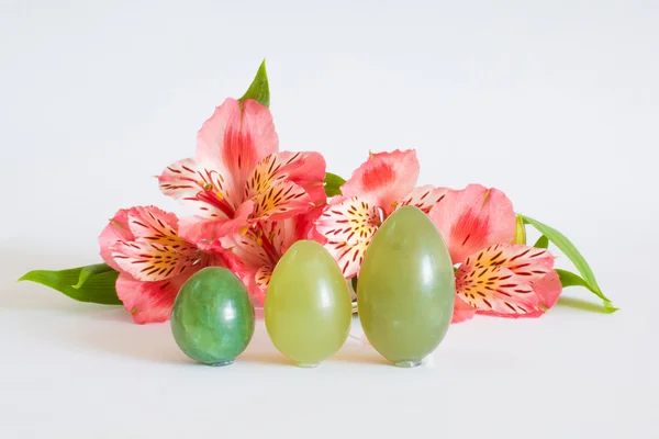 Le uova di giada stanno vicino a fiori rosa Foto Stock Royalty Free
