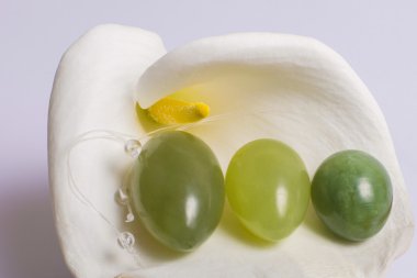 Jade eggs lie on a white flower clipart