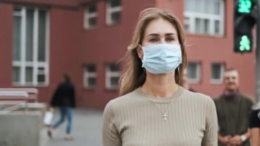 Sokakta yürüyen Corona virüsünü maskelemiş çekici bir kız. Kalabalık sağlıklı insanlar covid-19