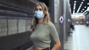 Maskeli insanlar metro koronavirüsünü bekliyor. Kadın Covid-19 istasyonunda duruyor..